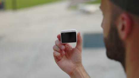 freelancer sosteniendo insta360 go 3 action pod sostenido en la mano izquierda afuera con vista a la pantalla trasera