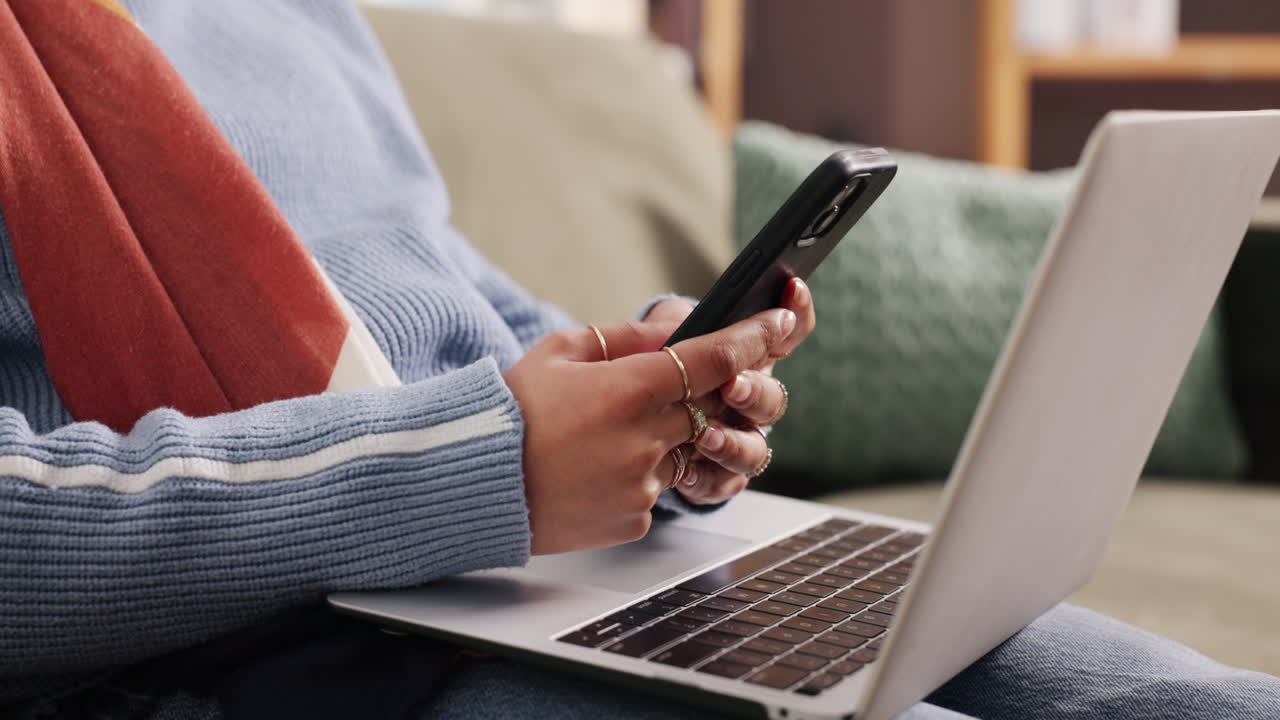 Woman using laptop and mobile phone on couch
