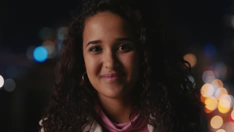 portrait beautiful mixed race woman on rooftop at night smiling happy enjoying urban nightlife with bokeh city lights in background