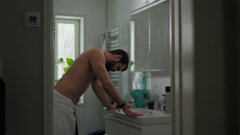 young man in the bathroom crestfallen with regret shaking head