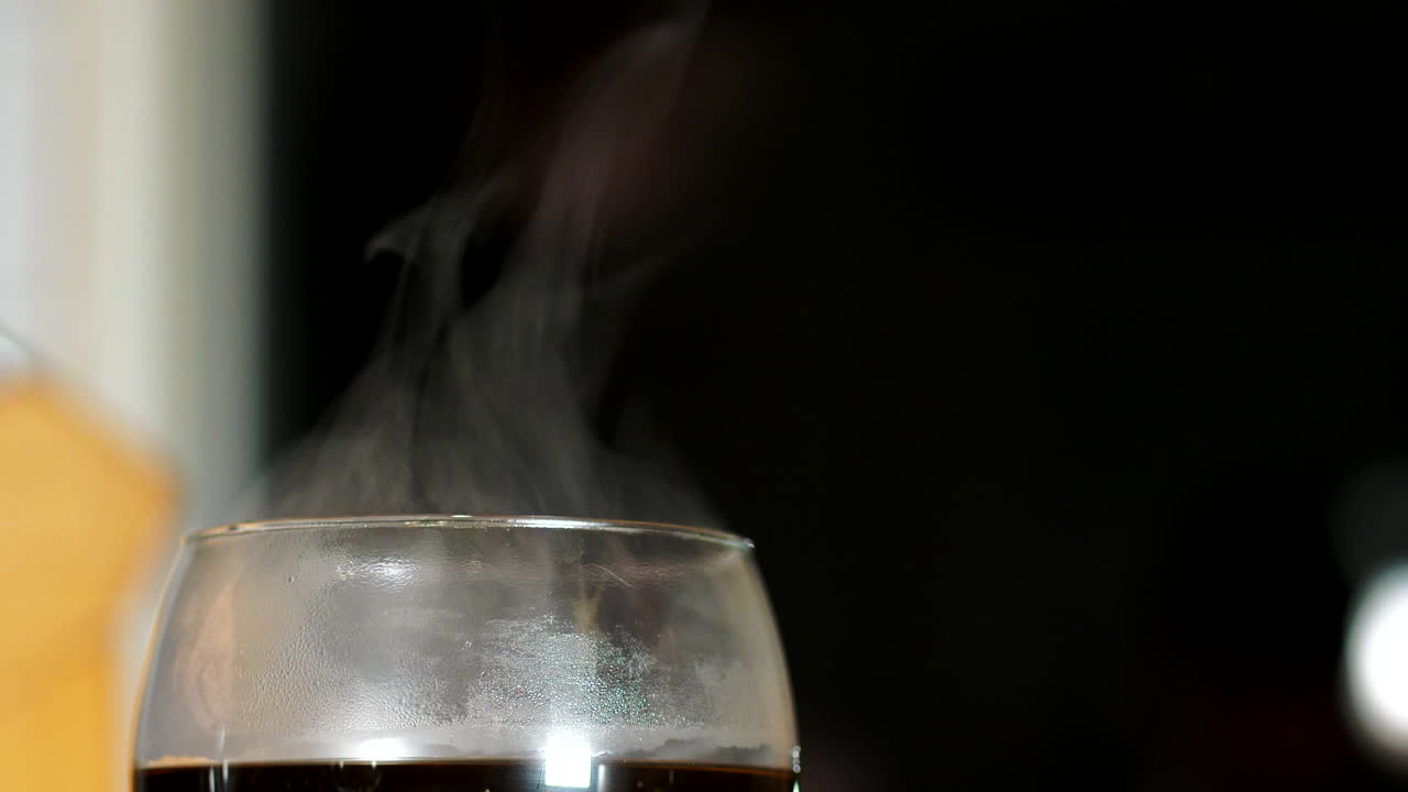 Afterski drink, Smoking Hot coffee in wine glass on black bokeh background