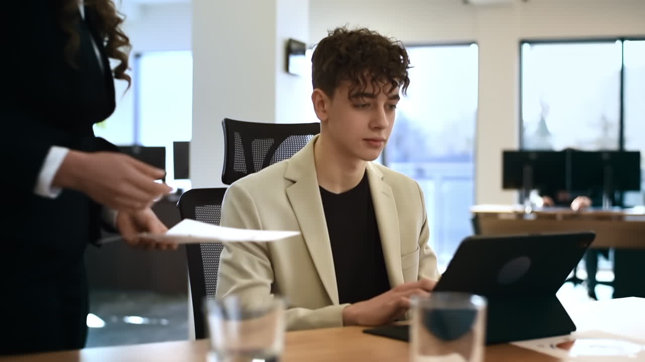 Female team leader discussing business affairs with a young worker. Business meeting at the office. Tablet on the table