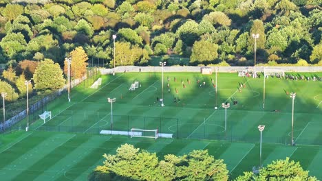 축구 선수 들 은 연습 을 위해 필드 에서 앞뒤로 달리는 동안 공 을  ⁇ 고, 드론 이 내려간다