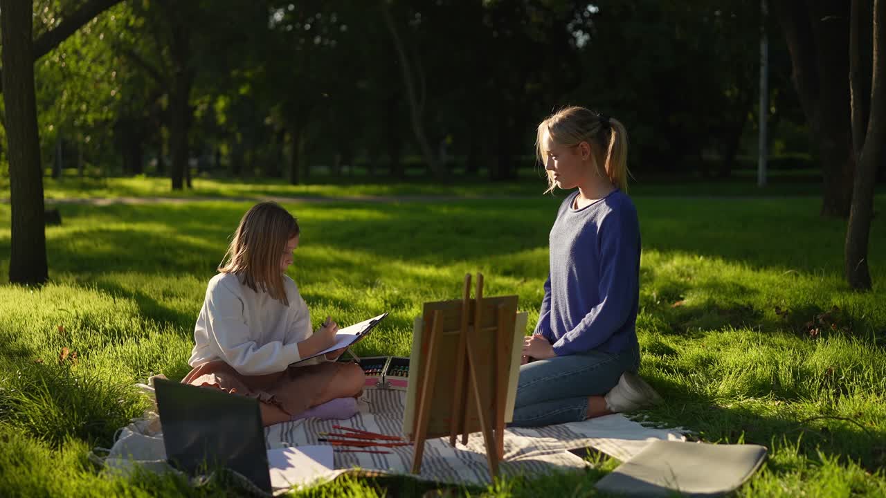 dos chicas pintando al aire libre en un parque