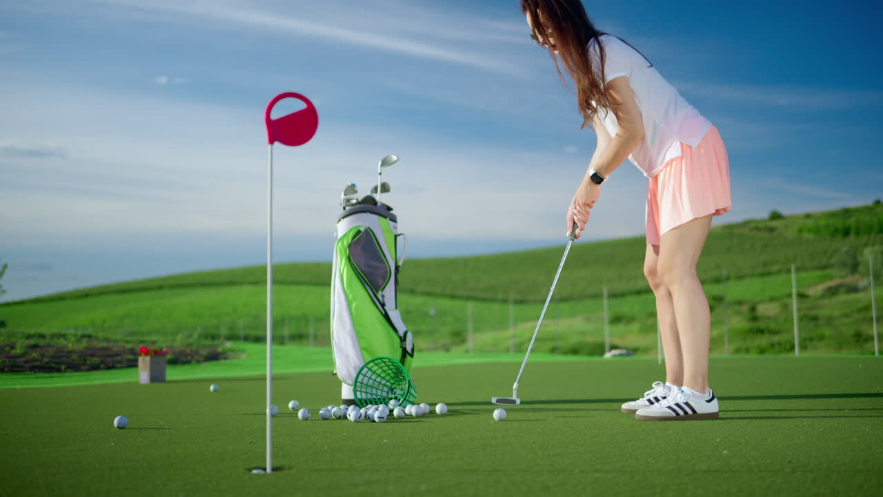 Woman dressed in white and pink playing golf near a cart bag on the course