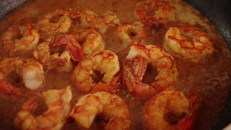 fresh and delicious prawns soaking in the bubbling sweet paprika sauce, slowly cooking, absorbing and thickening in shallow frying pan, extreme close up shot