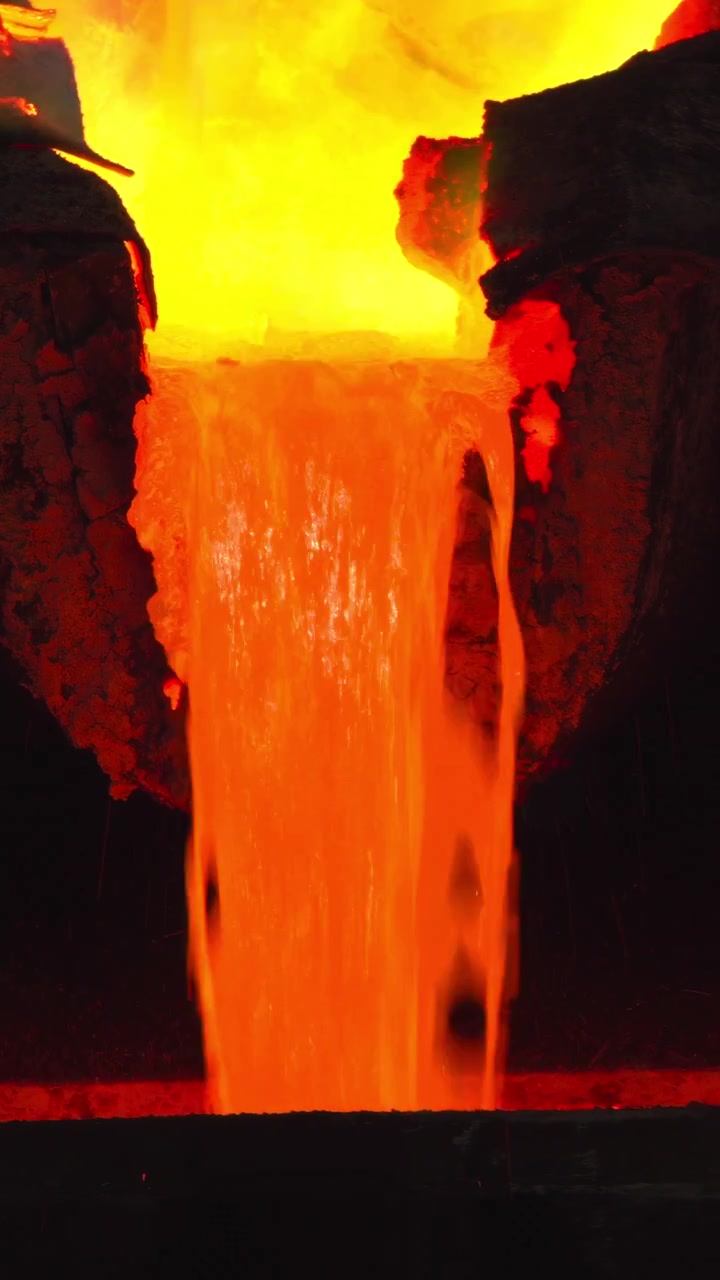Helles geschmolzenes Metall, das in eine Form gegossen wird, mit leuchtend orangefarbenem Fluss, grüner Dampffahne vom Flussmittel, Gießereiguss