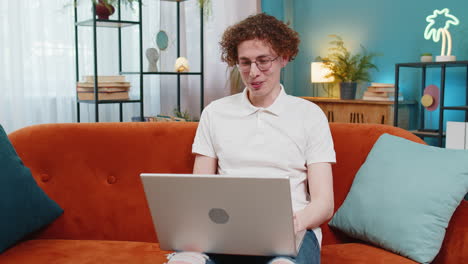 young man freelancer with laptop making video webcam conference call with colleagues waving hello