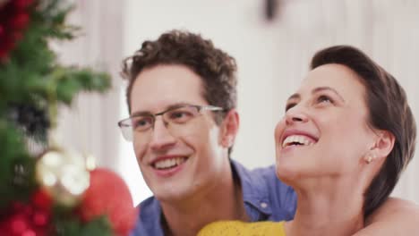 Happy-caucasian-couple-decorating-christmas-tree-at-christmas