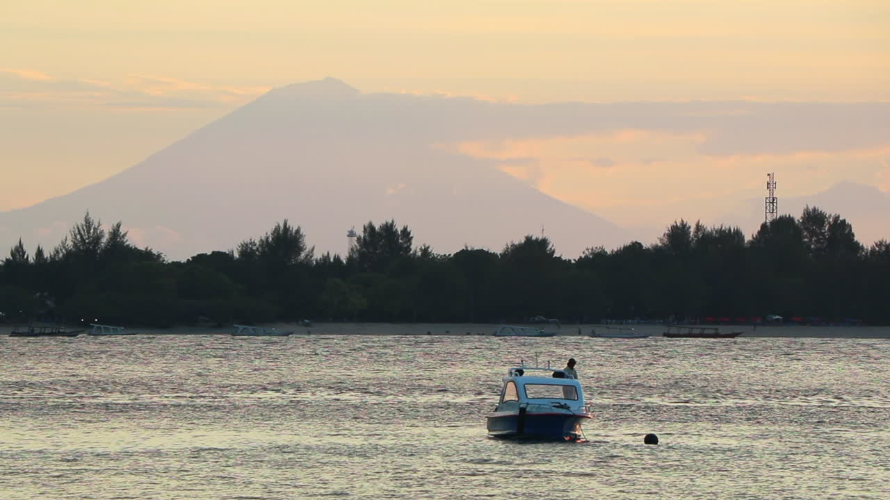 monte rinjani como vista desde las islas gili al atardecer con un barco flotando en la bahía