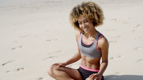 woman in sporty outfit sits on the sand