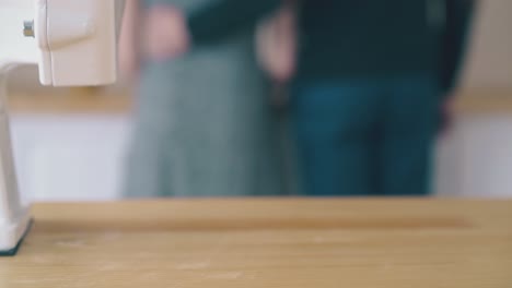 couple-cooks-with-homemade-flour-and-mill-at-wooden-table