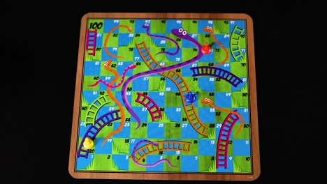 hand rolling dice on snakes and ladders board