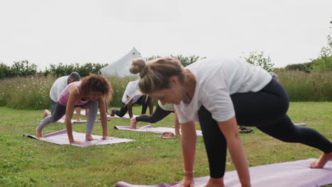 Lehrerin-Leitet-Eine-Gruppe-Reifer-Männer-Und-Frauen-Im-Unterricht-Bei-Einem-Yoga-Retreat-Im-Freien