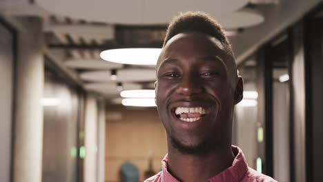 smiling african american man in business attire standing in modern office hallway