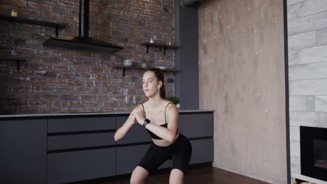 young woman working out at home in black athletic wear.