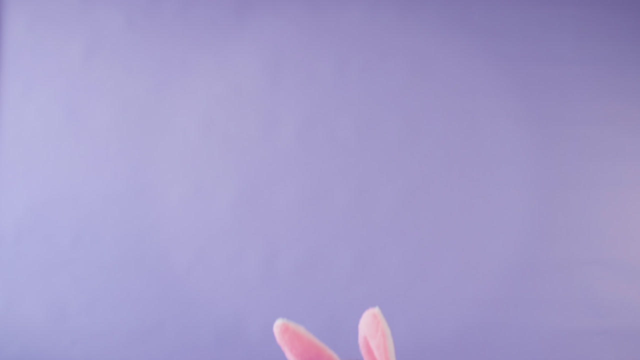 fotografía de estudio de una chica con orejas de conejo saltando desde la parte inferior del cuadro contra un fondo púrpura