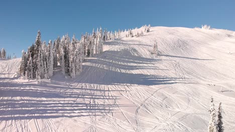 drone shot of a snowed mountain with snowmobile trails on the snow in revelstoke, canada