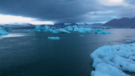 flight over jökulsárlón glacial lake in iceland at sunrise - drone shot