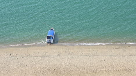 small boat anchored in sea by sandy tropical beach, high angle view