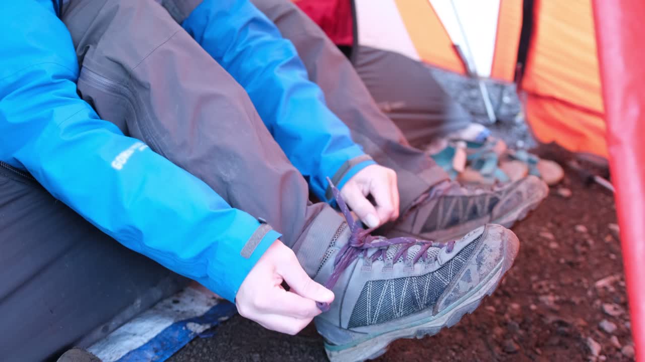 텐트 에 앉아 있는 관광객 이 신발 을 고 있다