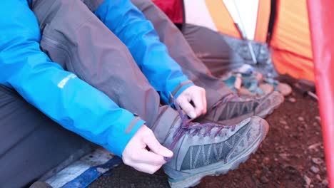 una turista atando sus cordones mientras está sentada en una tienda