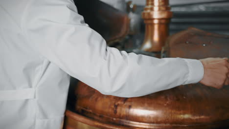 brewery worker operating copper brewing tank