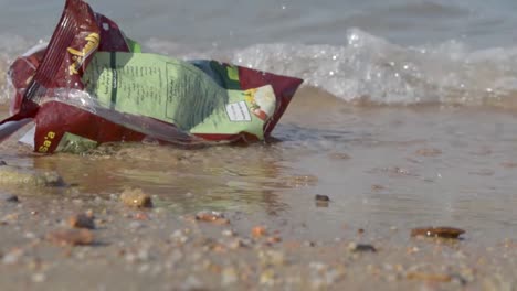 Leere-Snackverpackung-Aus-Plastik,-Die-Am-Strand-Zurückgelassen-Wurde-Und-Sich-In-Sanften-Wellen-Bewegte,-Teil-2,-Still