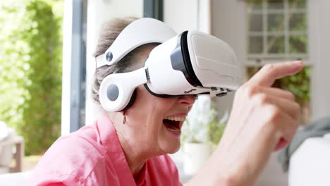 senior caucasian woman is engaged with a virtual reality headset, smiling broadly