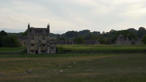 perfect summer evening in the english countryside in the cotswolds village of chipping campden with the old banqueting house and a flock of sheep at dusk