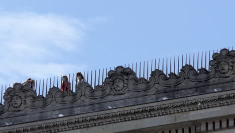 view from the ground of tourists wearing protective face masks on the roof of the arc de triomphe paris.