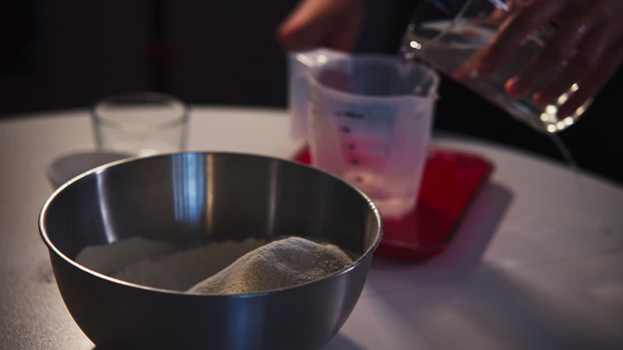 Mano che versa acqua in un misurino per ingredienti da forno