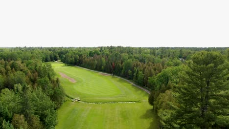 aerial view flying over a golf course fairway over a river