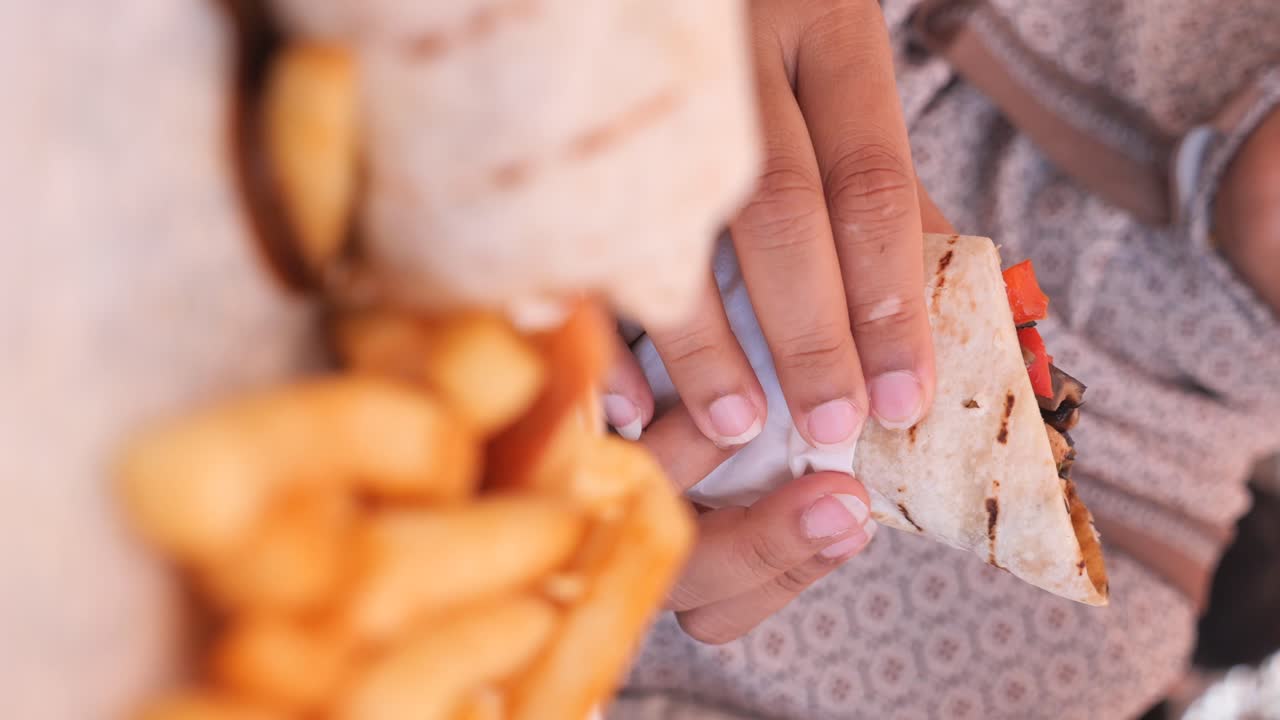 Person eating a wrap with fries