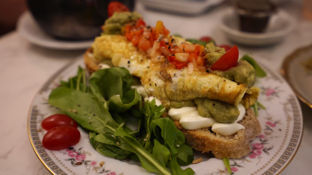 Healthy breakfast avocado toast served with egg, tomato, vegetables, cream cheese and whole-wheat bread in an antique plate