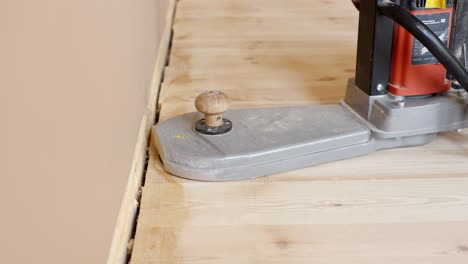 sanding edges of a wooden floor with a professional sanding machine close to the wall