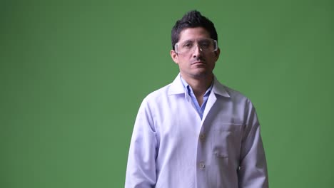 médico hispano con gafas protectoras cruzando los brazos