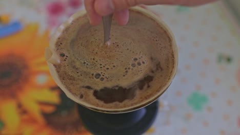 stirring a coffe bed in a dripper full of hot steamy coffe