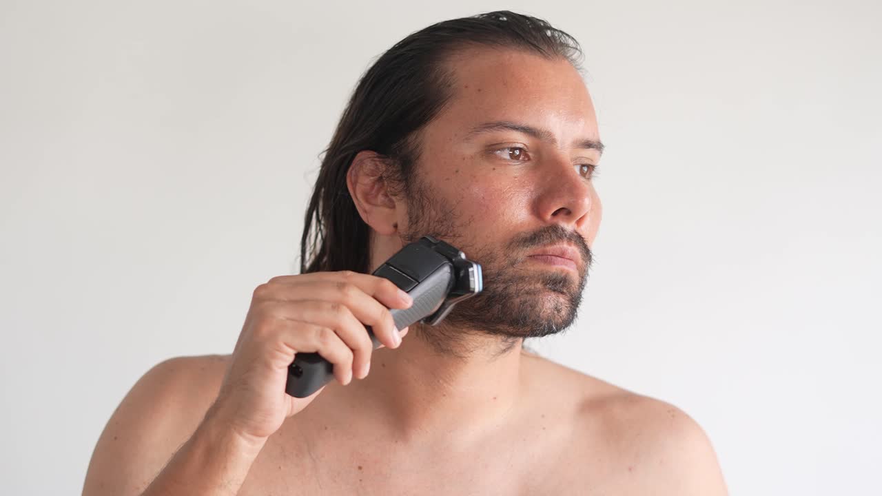 Man Shaving His Face with an Electric Shaver