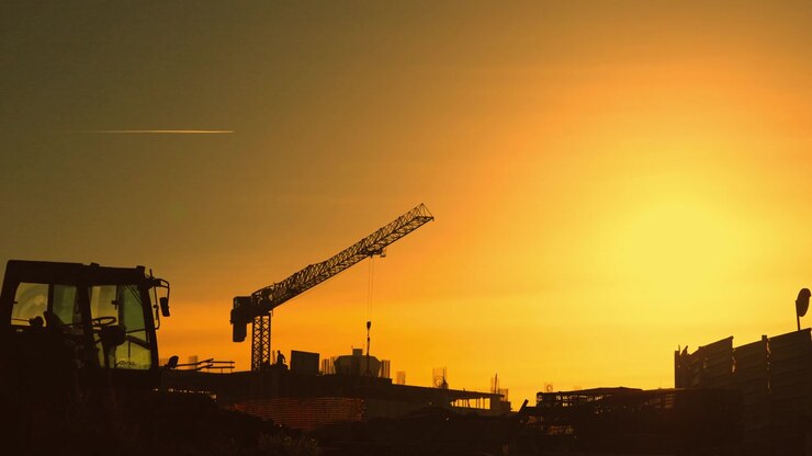 Construction site silhouettes with crane and machinery at sunset