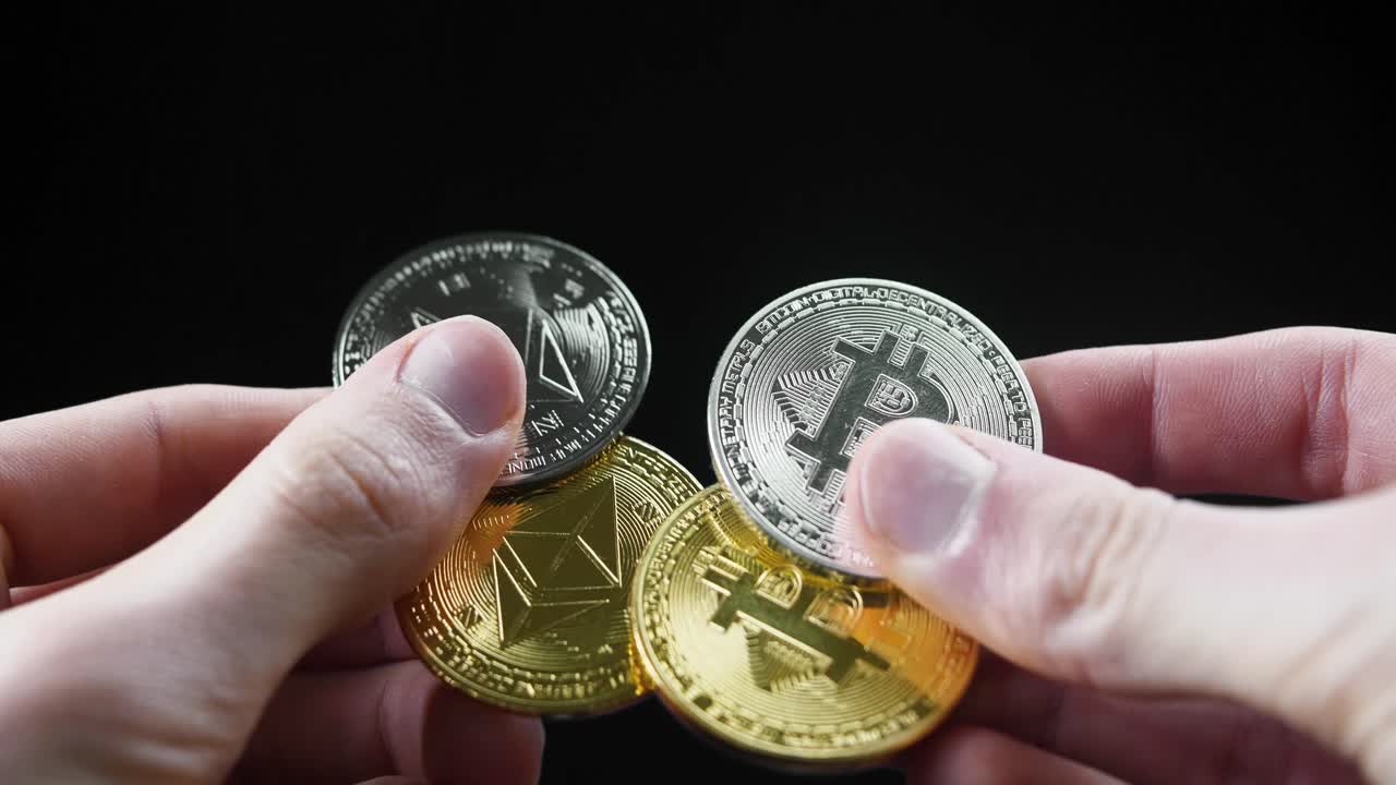 A close-up of two hands holding gold and silver Bitcoin and Ethereum coins on black background