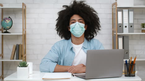 man wearing mask at laptop in office