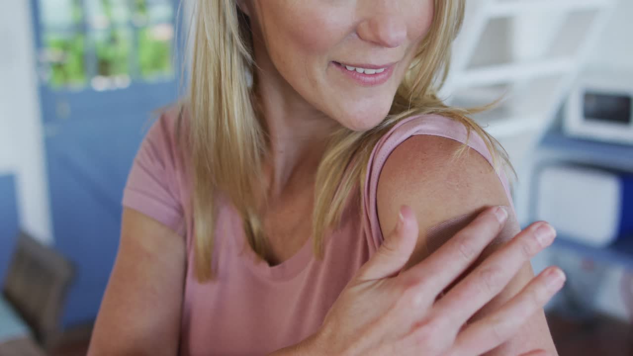 Mujer madura caucásica feliz mostrando una tirita en el brazo donde fue vacunada contra el coronavirus