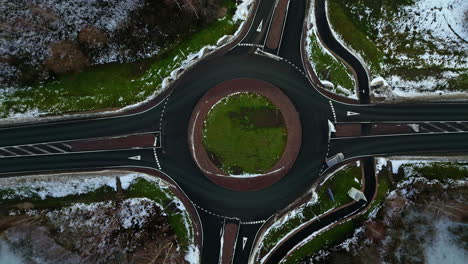 drop down view roundabout intersection in cold winter weather with light traffic and snow