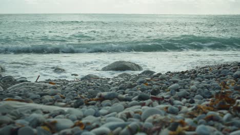 4K-Slow-motion-cinematic-scenery-shot-of-waves-hitting-rocks-on-a-pebble-beach,-at-Church-Ope,-Portland-Dorset,-in-England