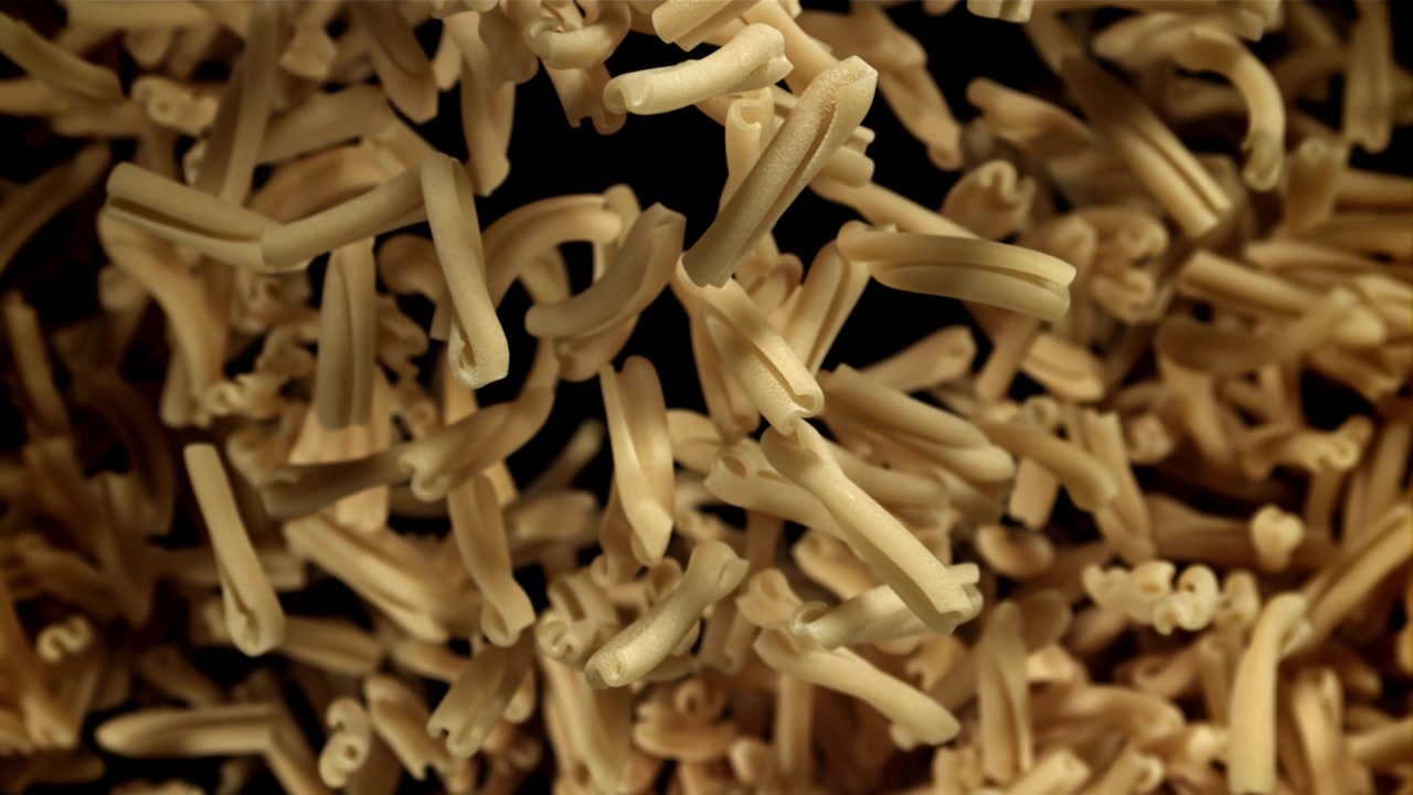 Uncooked Pasta Falling in Slow Motion on Black Background
