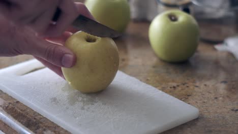 freshness in focus: cutting a green apple on board with two blurry apples in background