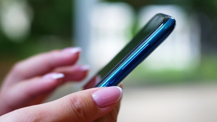 Una donna è seduta in un caffè con uno smartphone tra le mani con un mockup a schermo verde. La ragazza usa attivamente il telefono per i suoi scopi. Contenuti, video, blog