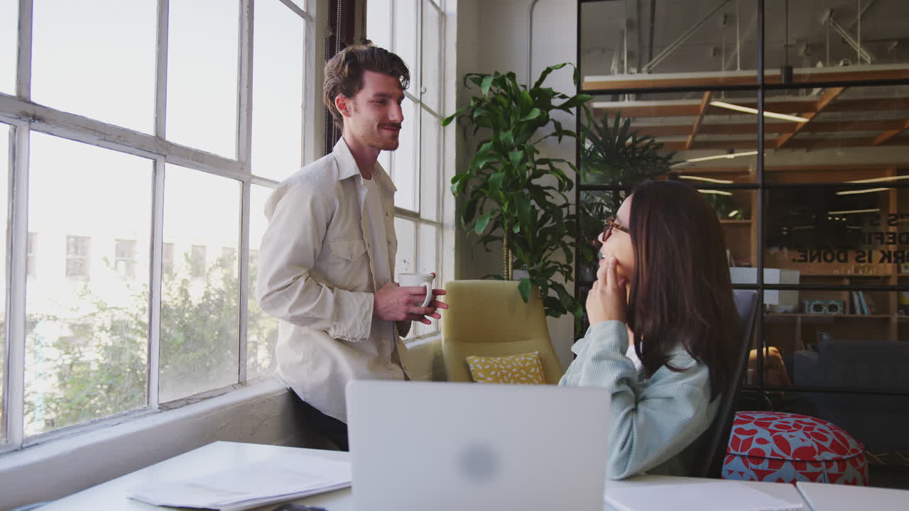 dos jóvenes colegas creativos tomando un descanso, hablando juntos en una oficina, de cerca