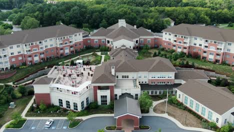 aerial pullback, apartments at senior living retirement home complex, multistory residential buildings and meeting space, american flag, united states of america, retirement and senior citizen aging